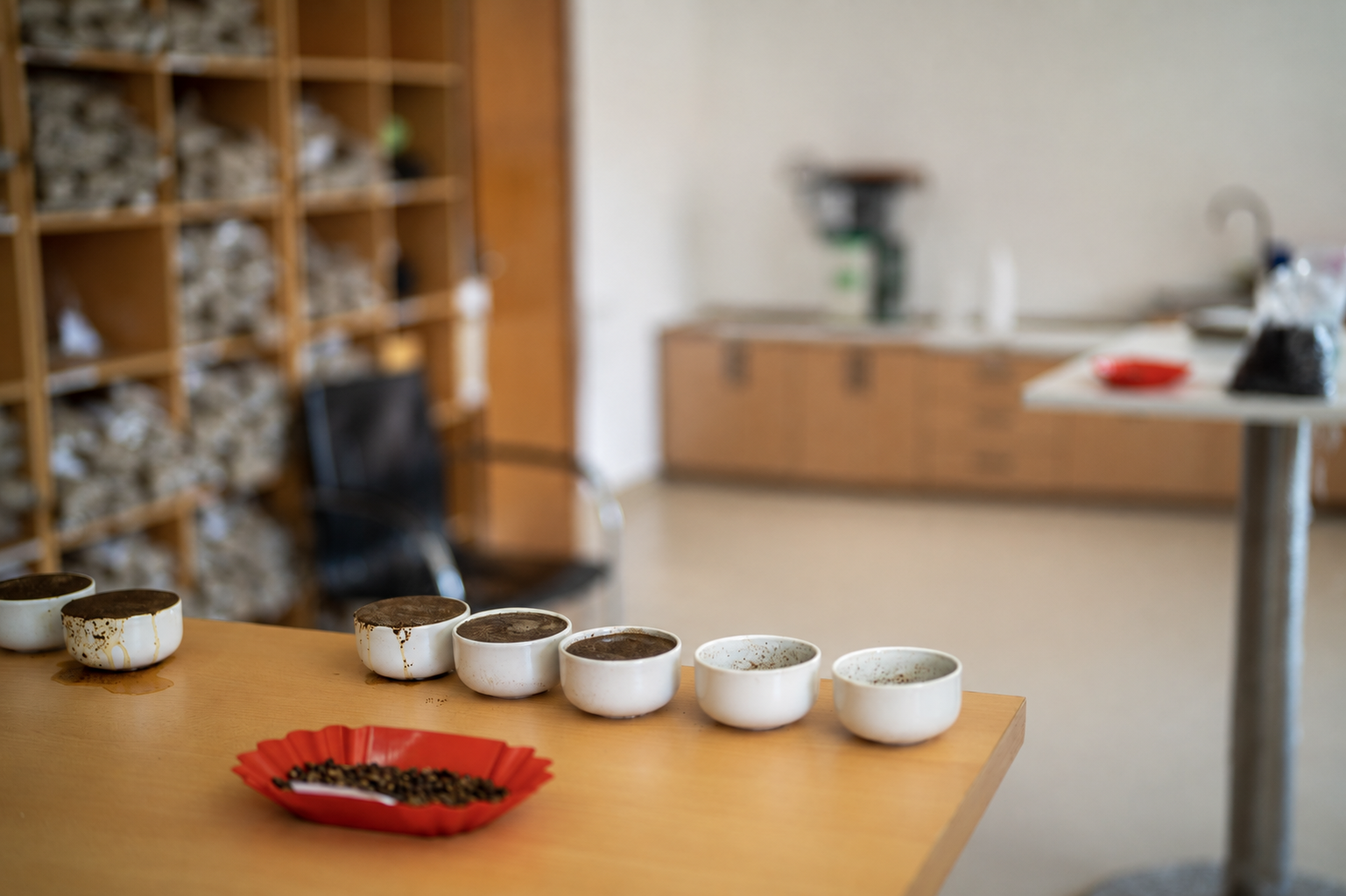 Xícaras de prova e amostras de café sobre uma mesa de laboratório. Imagem retocada para remover pessoas.